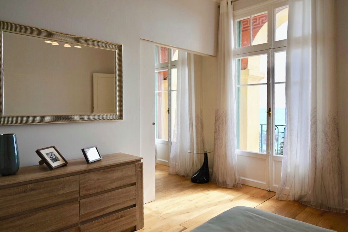 Une chambre à coucher avec une commode en bois, un grand miroir et un lit.