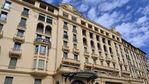 Un edifici d'àmples finestres i balcons, amb un rebedor central i una tenda.
