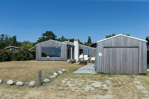 Une maison moderne dotée d’un grand garage, d’un patio couvert et d’une pelouse bien entretenue.