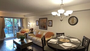 A dining area with a round table set for four, a sofa, and a chandelier. - Times Square Next To Rogers Place #205 (EDMONTON)