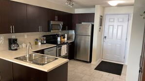 A modern kitchen with dark cabinets, stainless steel appliances, and a central island. - Times Square Next To Rogers Place #205 (EDMONTON)