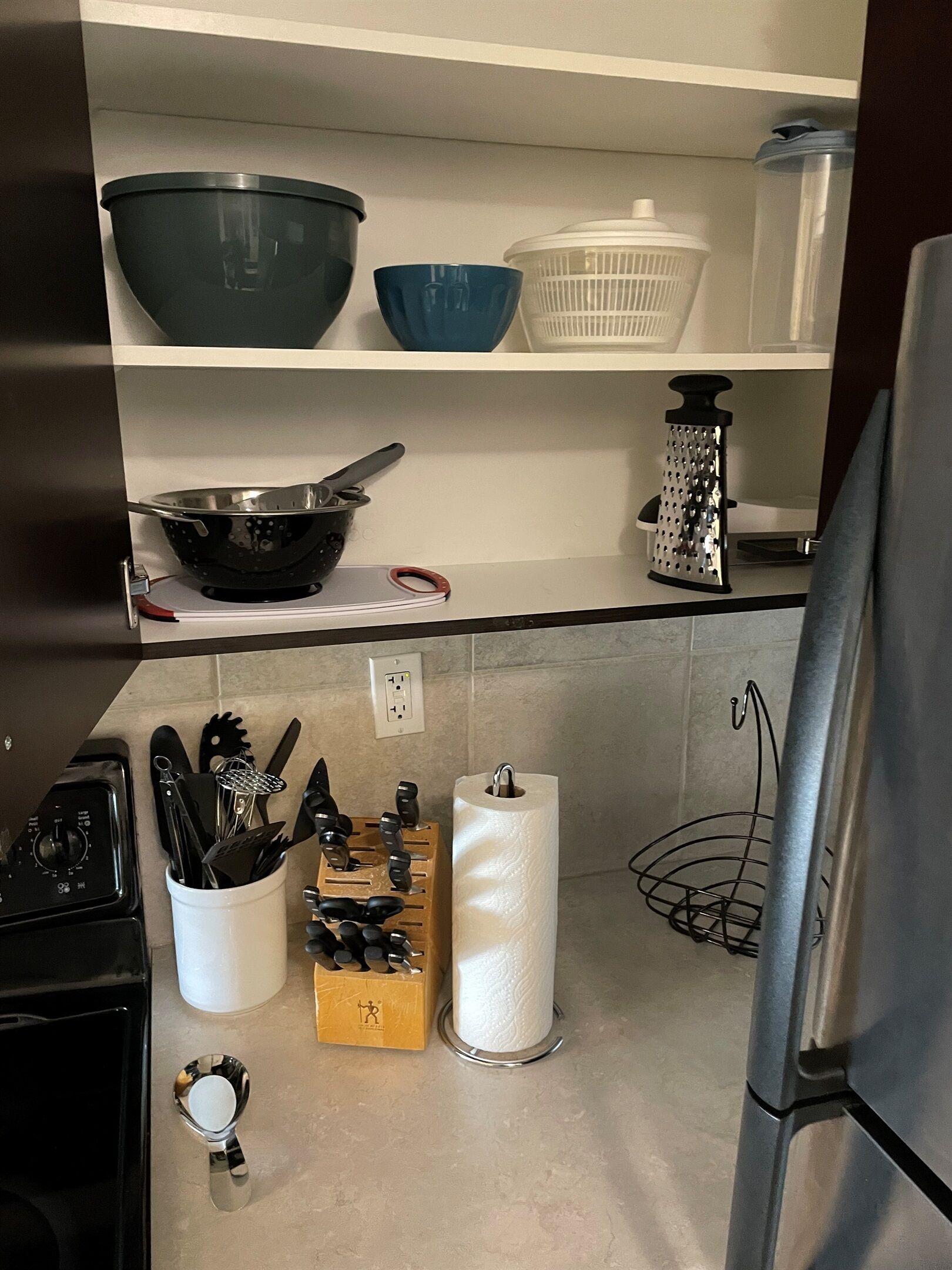 A kitchen with a stove, a sink, a cutting board, and various utensils.