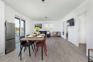 Eine moderne Küche mit Esstisch, Stühlen, einem Kühlschrank und einem an der Wand befestigten Fernseher.