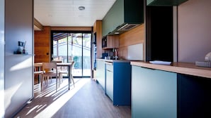 Eine moderne Küche mit Essbereich aus Holz, integrierten Geräten und Blick durch die Glastür.