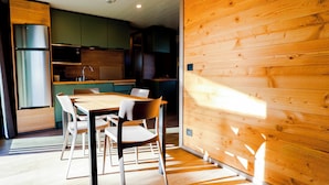 Eine moderne Küche mit Holzausstattung, einem Edelstahlkühlschrank und einem Essbereich mit Holztisch und -stühlen.