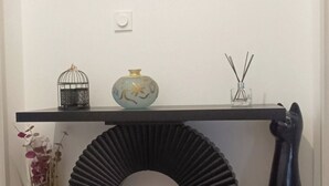 En modern inredning med ett svart konsolbord, en dekorativ svart skulptur, en spegel och en väggmonterad luftkonditioneringsenhet.