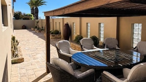 Une terrasse extérieure avec une table ronde et des chaises, entourée de cactus et de plantes en pot.