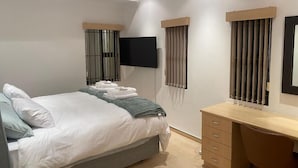 Une chambre à coucher moderne, équipée d’un lit, d’un bureau et d’une télévision.