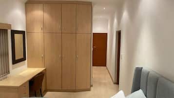 A bedroom with a bed, a desk, and a wardrobe.