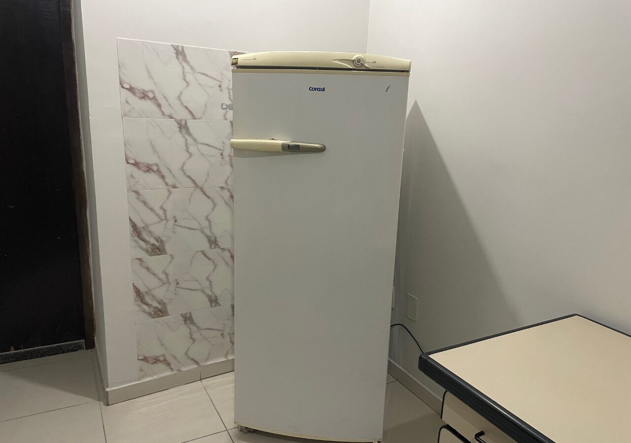 Un refrigerador blanc amb un tancament digital, una paret amb dibuixos de marbre i una taula de superfície clara.
