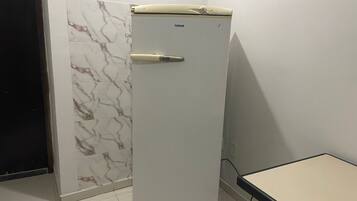 Un refrigerador blanc amb un tancament digital, una paret amb dibuixos de marbre i una taula de superfície clara.