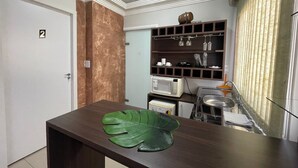 A compact kitchen with a microwave, a sink, and a small countertop. - 474flats e Suítes Standart  (Ipatinga)