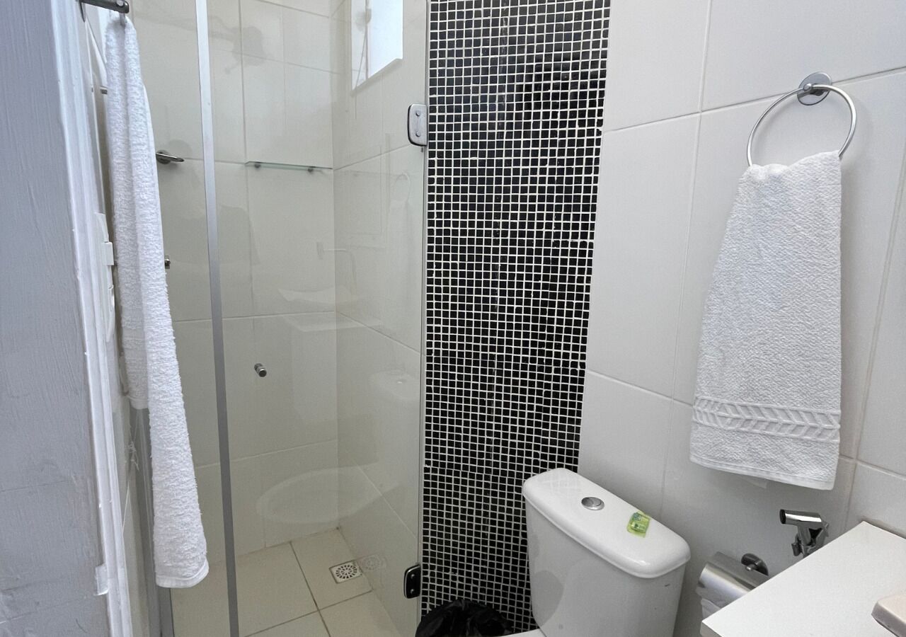 A bathroom with a glass shower enclosure, a toilet, and a sink.