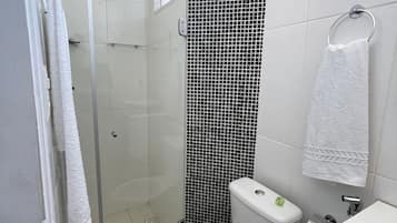 A bathroom with a glass shower enclosure, a toilet, and a sink.