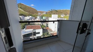 A balcony with a view of buildings and a hill. - 474flats e Suítes Standart  (Ipatinga)