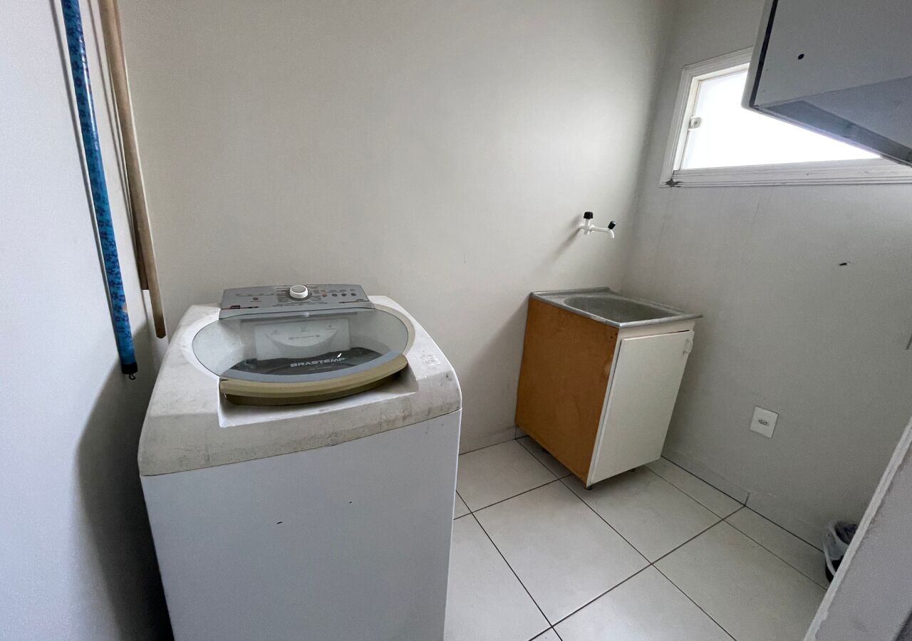 Un área de lavandería compacta con lavadora y secadora, una ventana pequeña y piso de baldosas.