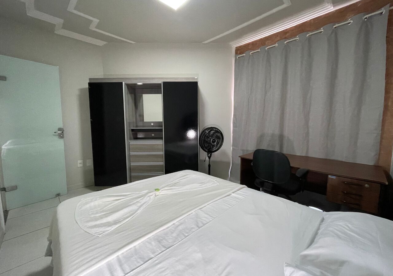 Hotellihuone, jossa on sänky, työpöytä, tuoli, vaatekaappi ja tuuletin.