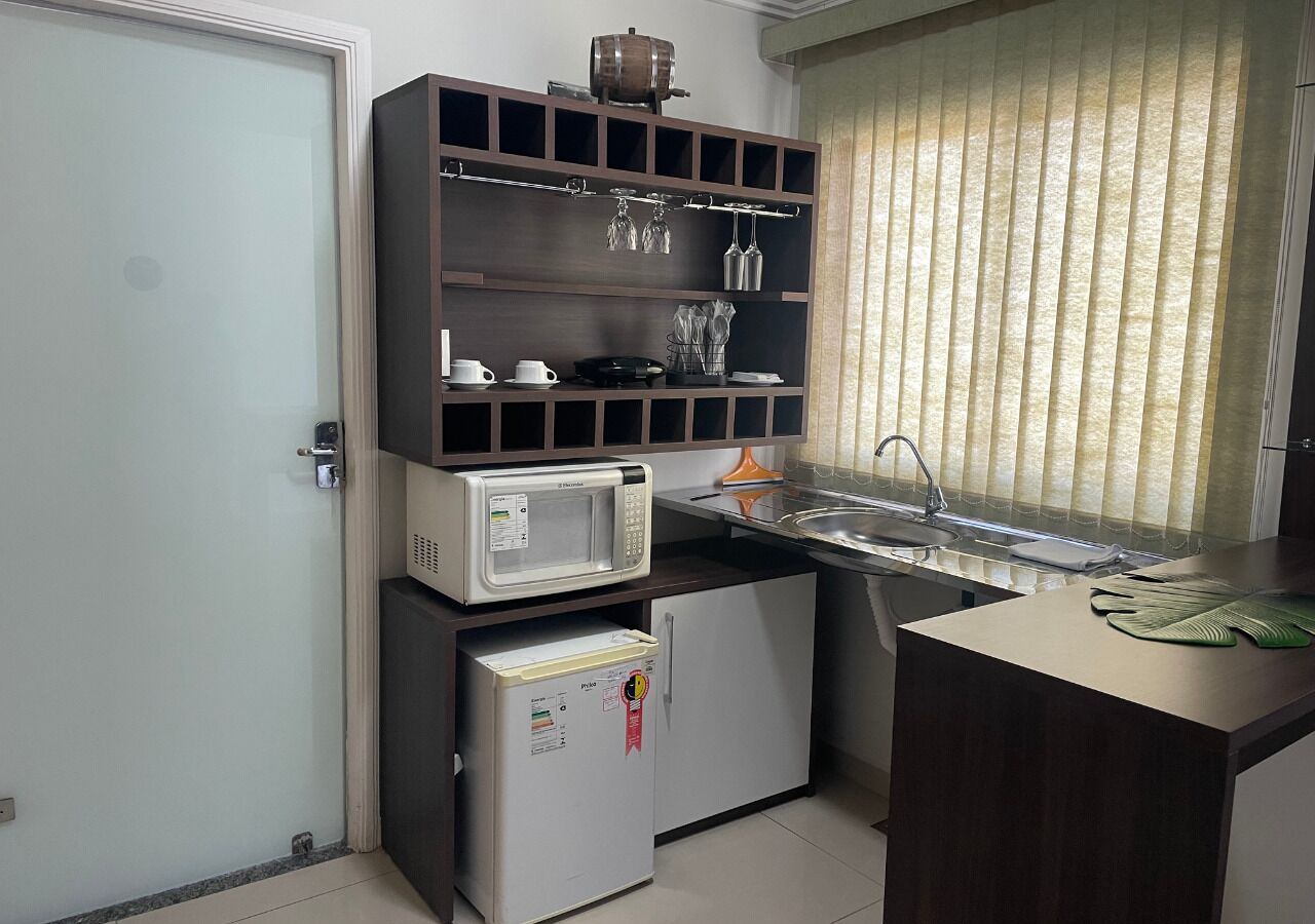 A compact kitchen with a microwave, refrigerator, and a sink.