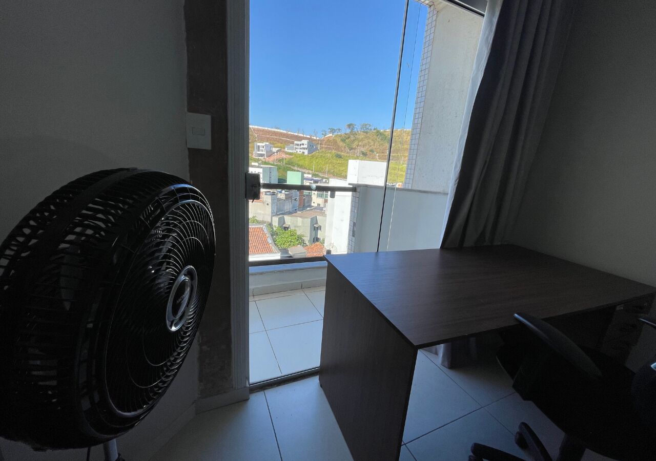Un balcón con vistas a edificios y un ventilador en la habitación.