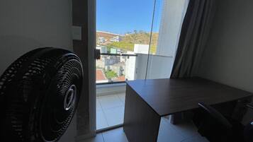 Un balcón con vistas a edificios y un ventilador en la habitación.