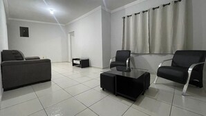 A modern living room with a sofa, two chairs, a coffee table, and a small side table. - 474flats e Suítes Standart  (Ipatinga)