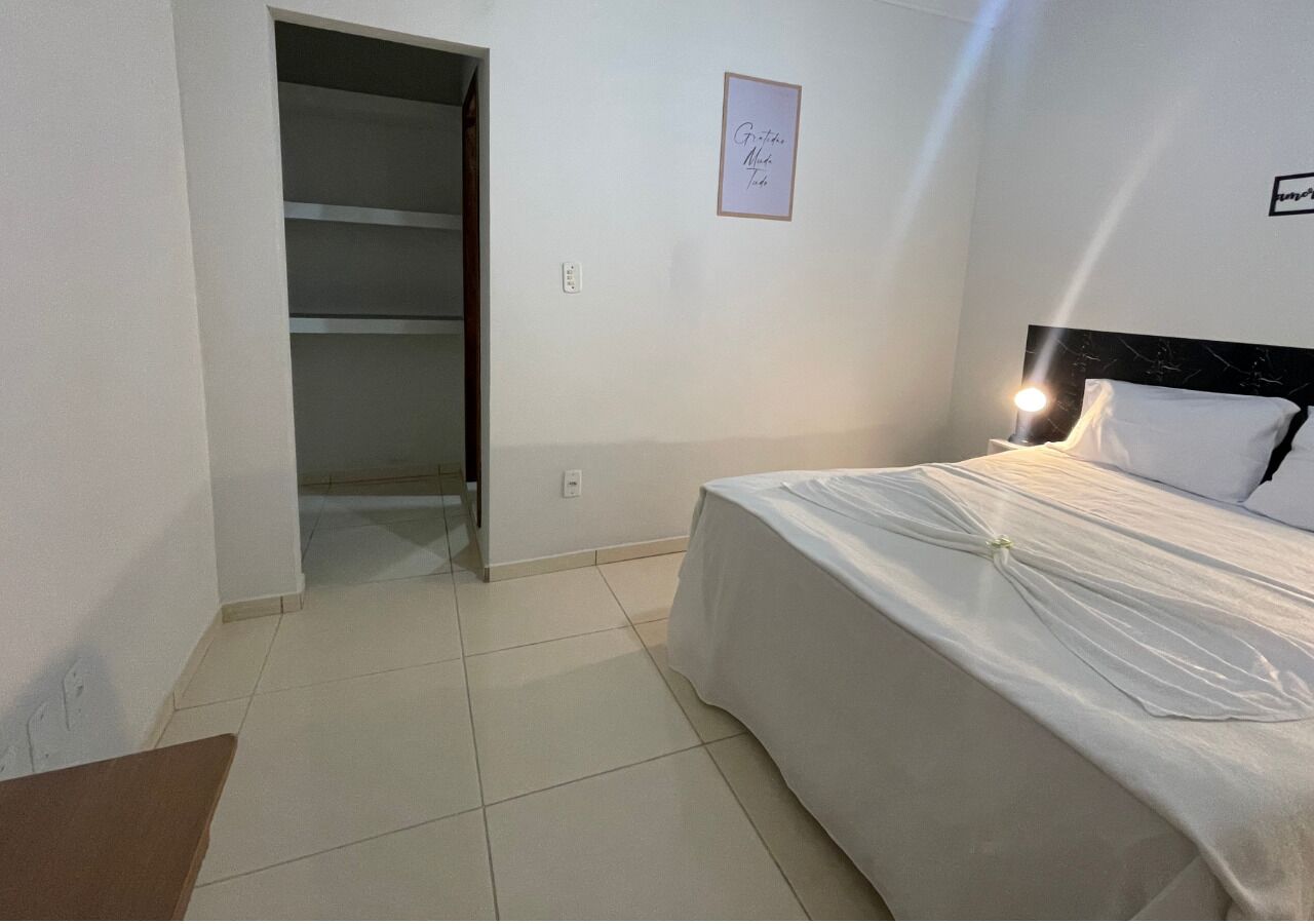 Un dormitorio con cama, mesita de noche, armario y un cuadro en la pared.