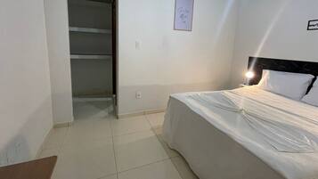 Un dormitorio con cama, mesita de noche, armario y un cuadro en la pared.