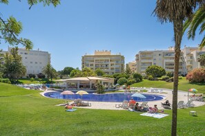 A pool area with lounge chairs, umbrellas, and a covered seating area. - 'Casinha Marachique' Apartment with Shared Pool, Wi-Fi, and Air Conditioning (Alvor)