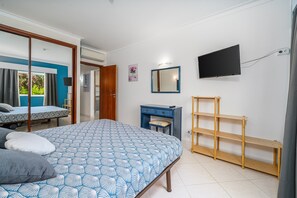 A bedroom with a bed, a desk, a TV, and a window with curtains. - 'Casinha Marachique' Apartment with Shared Pool, Wi-Fi, and Air Conditioning (Alvor)