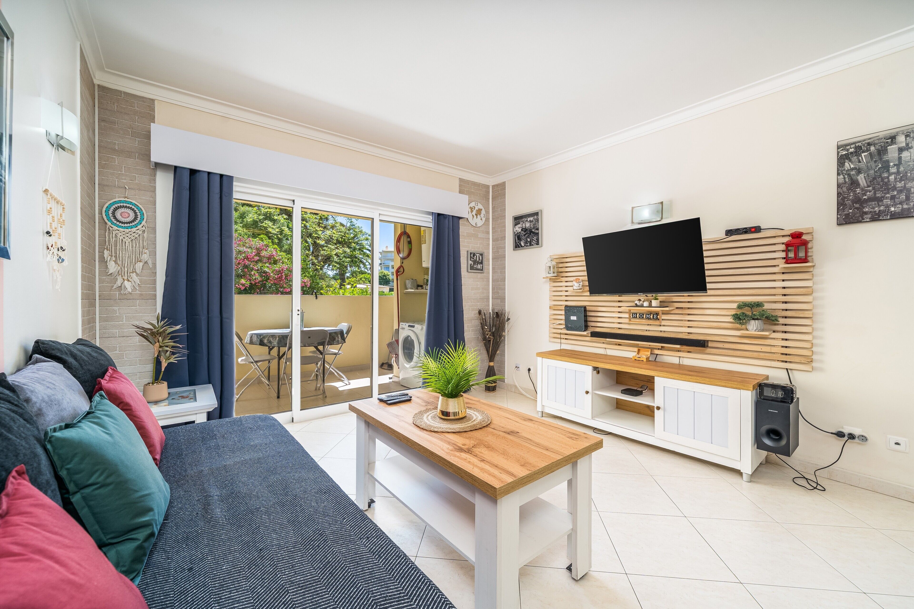 A living room with a sofa, a coffee table, a TV, and a sliding glass door leading to an outdoor area.