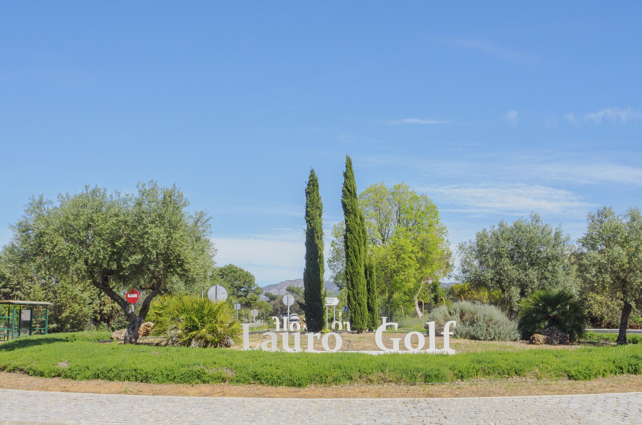 A sign for "Lauro Golf" with a clear sky and greenery.