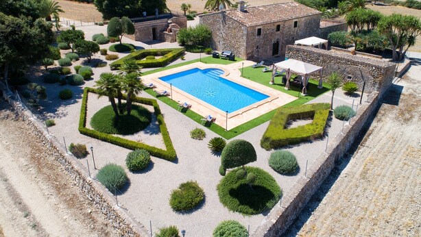 Eine Luftaufnahme eines Anwesens mit Swimmingpool, Steinhaus und angelegtem Garten.