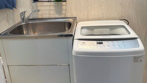 A compact kitchen with a built-in dishwasher, a stainless steel sink, and a window with potted plants. - Separate private room In Sydney region (Hebersham)
