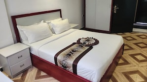 A hotel room with a bed, a nightstand, a wardrobe, and a patterned floor. - Safe Addis Hotel and Spa (Addis Ababa)