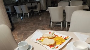 A dining table with a plate of food, a cup, and a spoon. - Safe Addis Hotel and Spa (Addis Ababa)