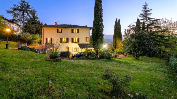 A two-story house with a garden, a car parked in front, and a clear sky. - 300-square-meter villa · 6 bedrooms & 5 bathrooms · Cool in the summer (Bibbiena)