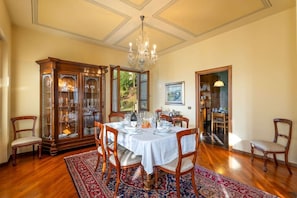 A dining room with a round table, chairs, a chandelier, and a cabinet with glass doors.