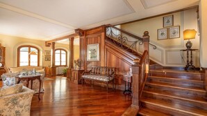 A spacious living room with a wooden staircase, a sofa, a bench, and a lamp. - 300-square-meter villa · 6 bedrooms & 5 bathrooms · Cool in the summer (Bibbiena)