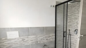 A modern bathroom with a toilet, bidet, and glass-enclosed shower. - Apartment 'Perla' with Sea View, Balcony and Air Conditioning (Agrustos)