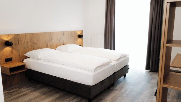 Una cama doble con cabecera de madera, una mesita de noche y un armario.