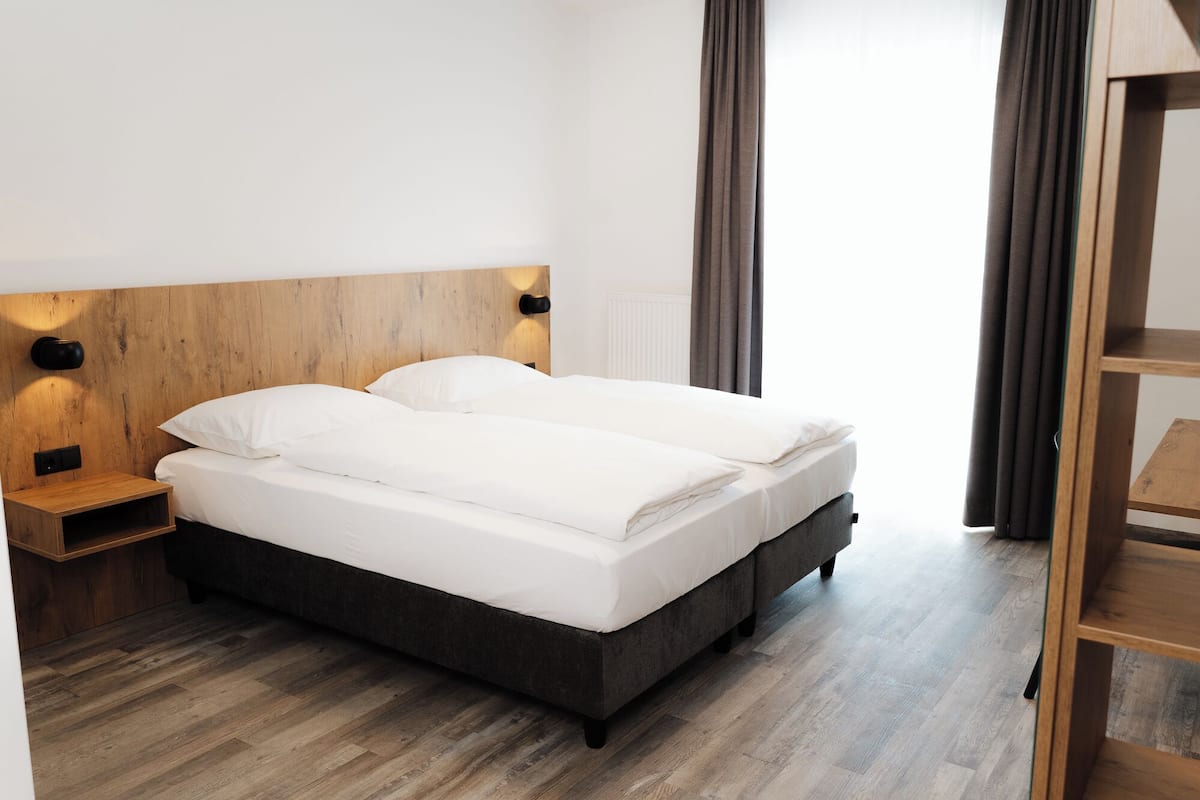 Un lit double avec une tête de lit en bois, une table de chevet et une armoire.
