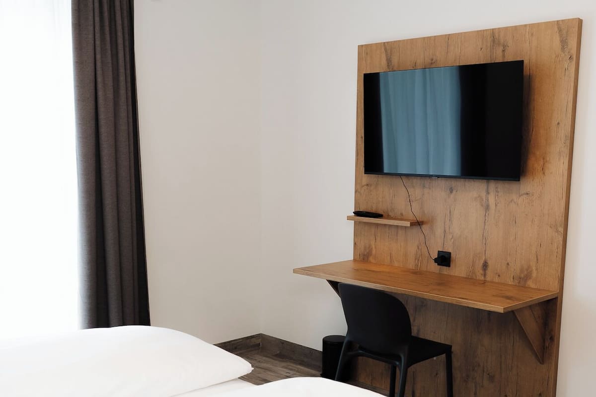 Une chambre d’hôtel comprenant un lit, un bureau avec un téléviseur à écran plat et une chaise.
