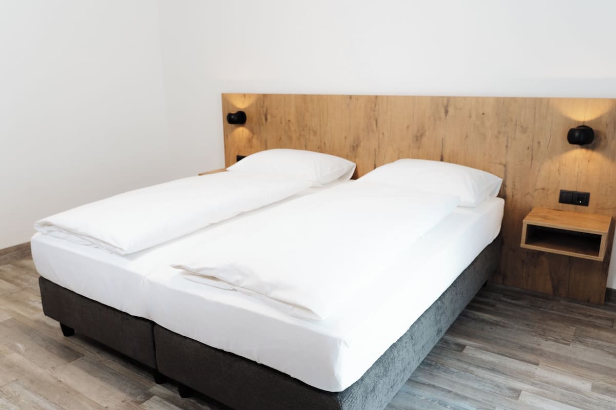 Un lit double avec une tête de lit en bois, une table de chevet avec une lampe et un plancher en bois.