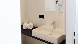 Un baño moderno con un lavabo blanco, un espejo y un perchero para toallas.