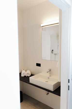 Ein modernes Badezimmer mit einem weißen Waschbecken, einem Spiegel und einem Handtuchhalter.