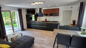 Een moderne keuken met zwarte kastjes, een inbouwoven en een eethoek met een tafel en stoelen.