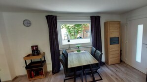 Een gezellig hoekje om te eten, met een tafel, stoelen, een koffieapparaat, een kast en een raam met gordijnen.