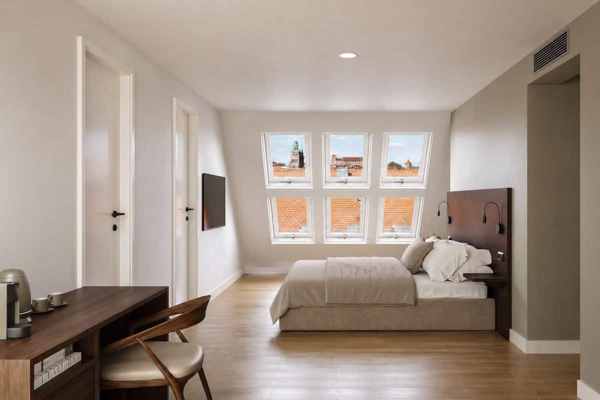 A bedroom with a bed, a desk, a chair, and a TV.