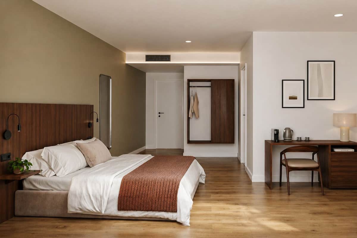 A bedroom with a bed, bedside table, desk, chair, and a door leading to another room.