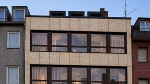 Um edifício moderno com vários andares, janelas amplas e um espaço comercial no térreo.